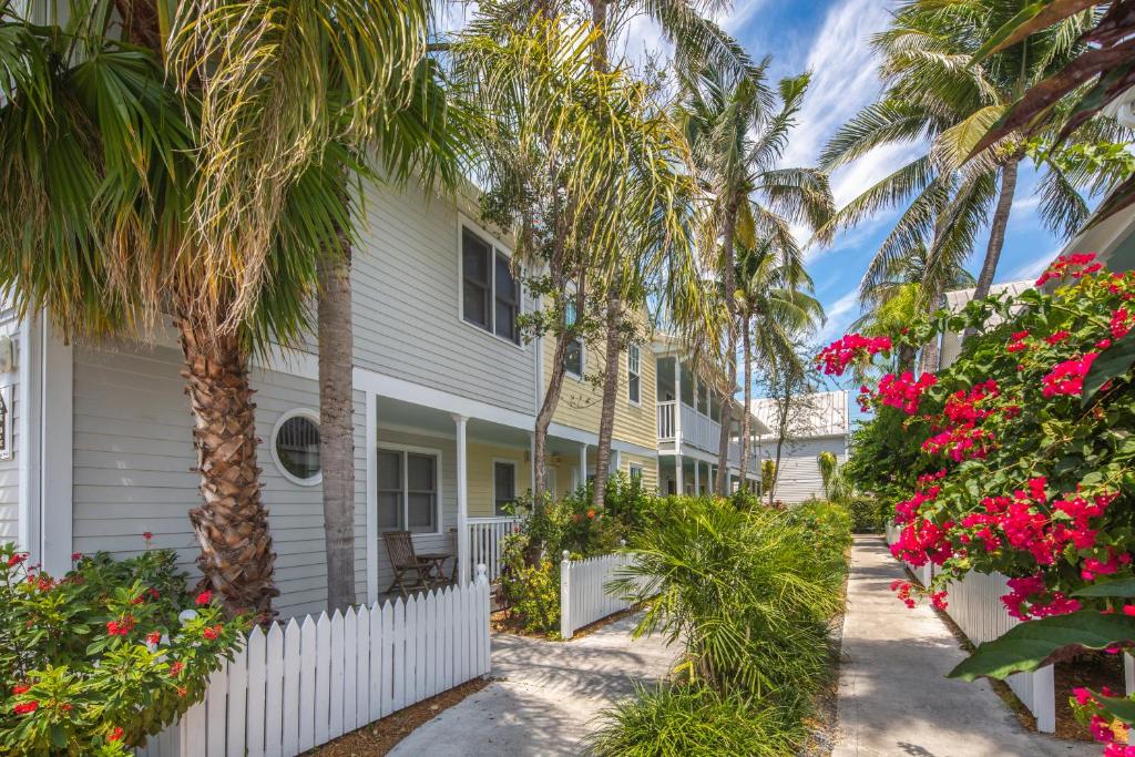 a white house with palm trees and flowers at Shipyard Perch in Key West