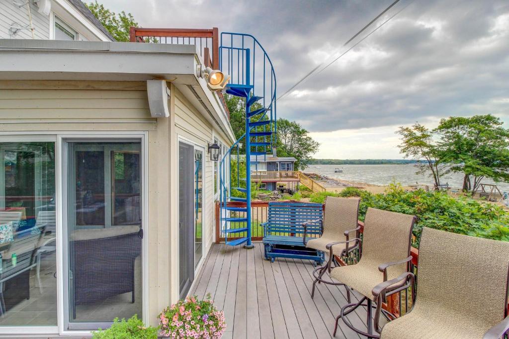 a house with chairs and a deck with a view of the water at Broadlake in Thayer Beach