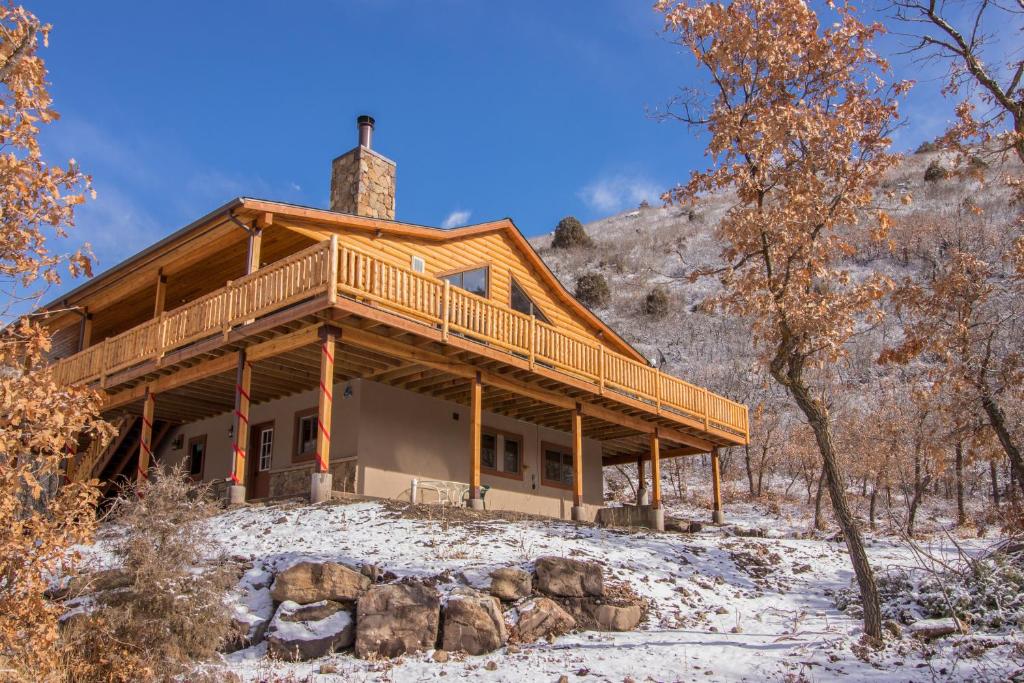 a log home with a wrap around deck in the snow at Hawk Perch in Durango