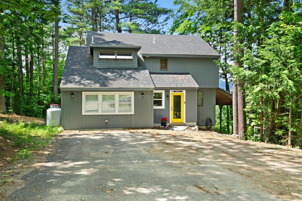 ein graues Haus mit einer Einfahrt im Wald in der Unterkunft New England Treasure in North Conway