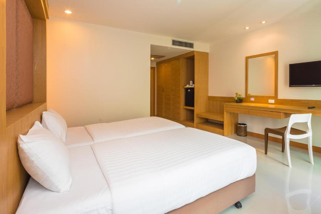 a bedroom with a bed and a desk and a television at Sungthong Kamala Beach Resort in Kamala Beach