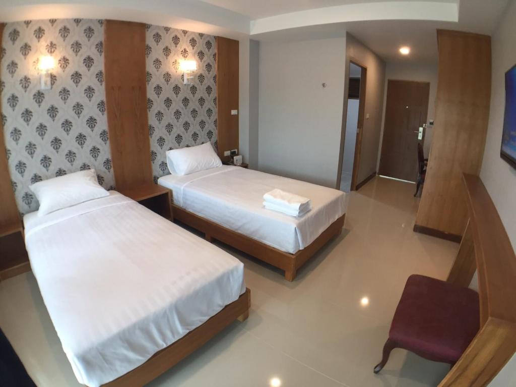 a hotel room with two beds and a chair at Nantawan Hotel in Ban Fang Min