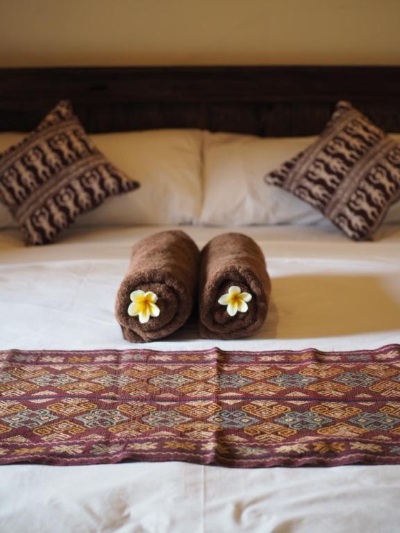 two brown towels with flowers on a bed at Kampung Sari Homestay in Ubud