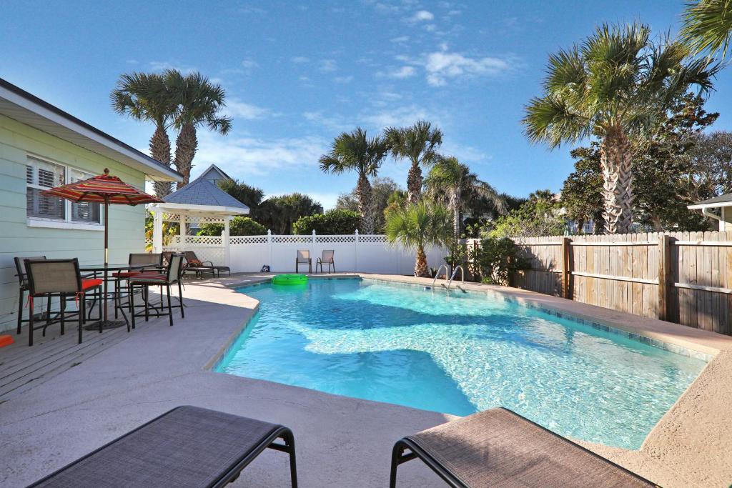 a swimming pool in a backyard with a table and chairs at Beachy Keen in Jacksonville Beach