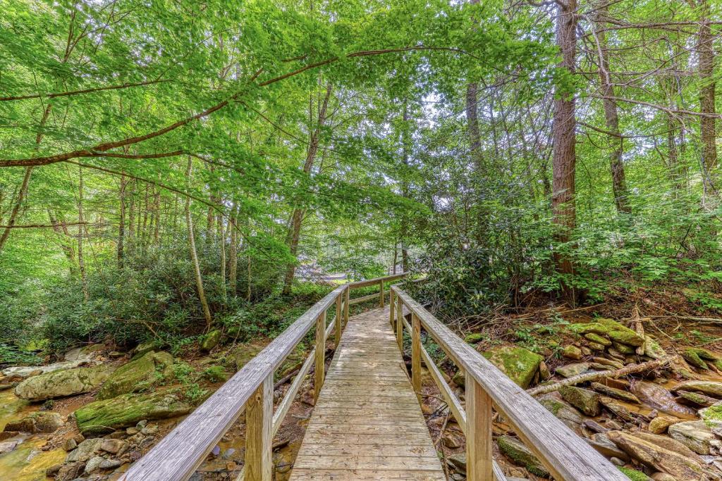 eine Holzbrücke in einem Wald mit Bäumen in der Unterkunft Bee Branch 27 in Sugar Mountain