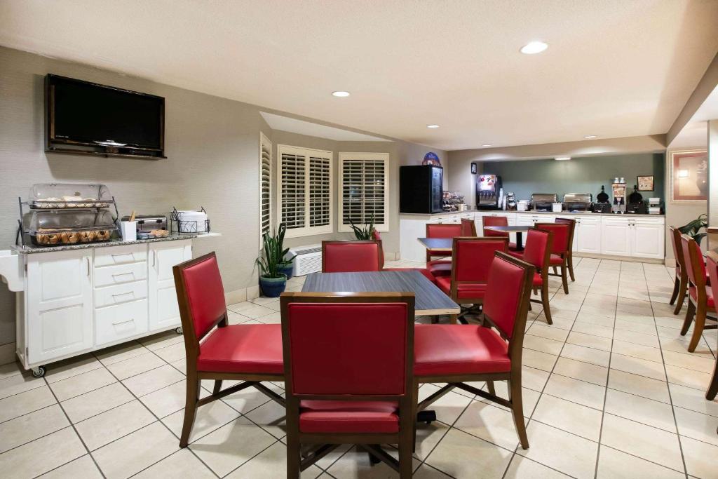 a restaurant with red chairs and tables and a kitchen at Baymont Inn & Suites Braselton in Braselton