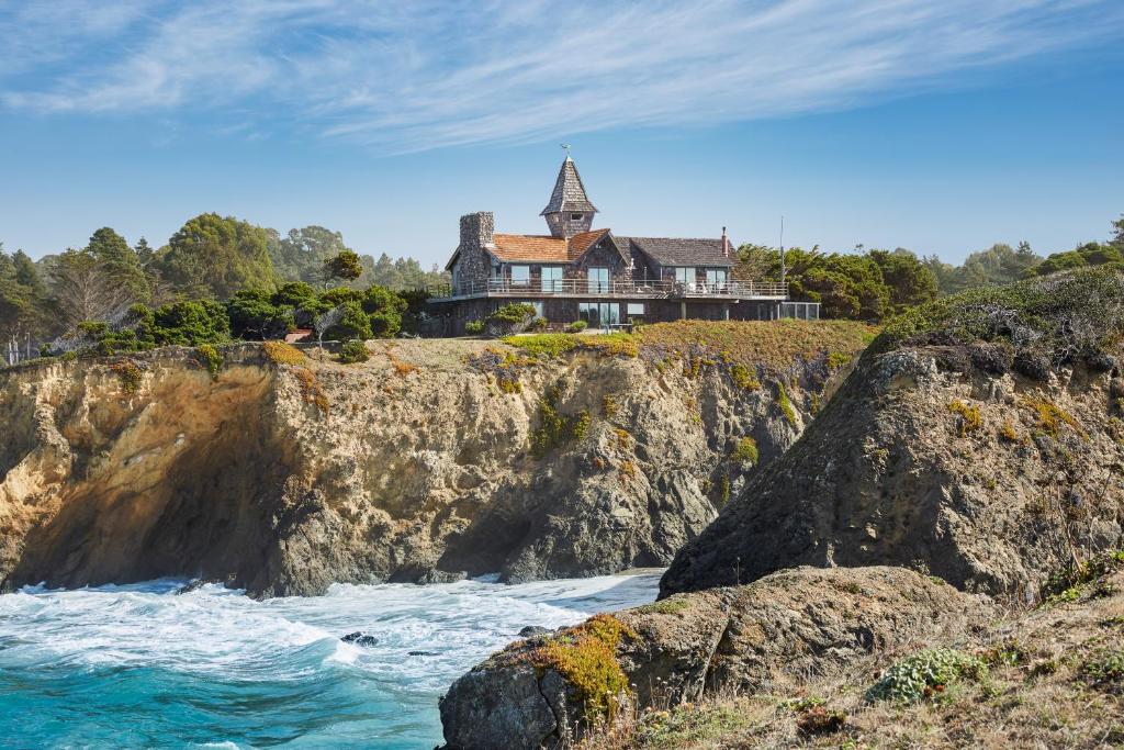 a house on top of a cliff next to the water at Ocean Breeze in Fort Bragg