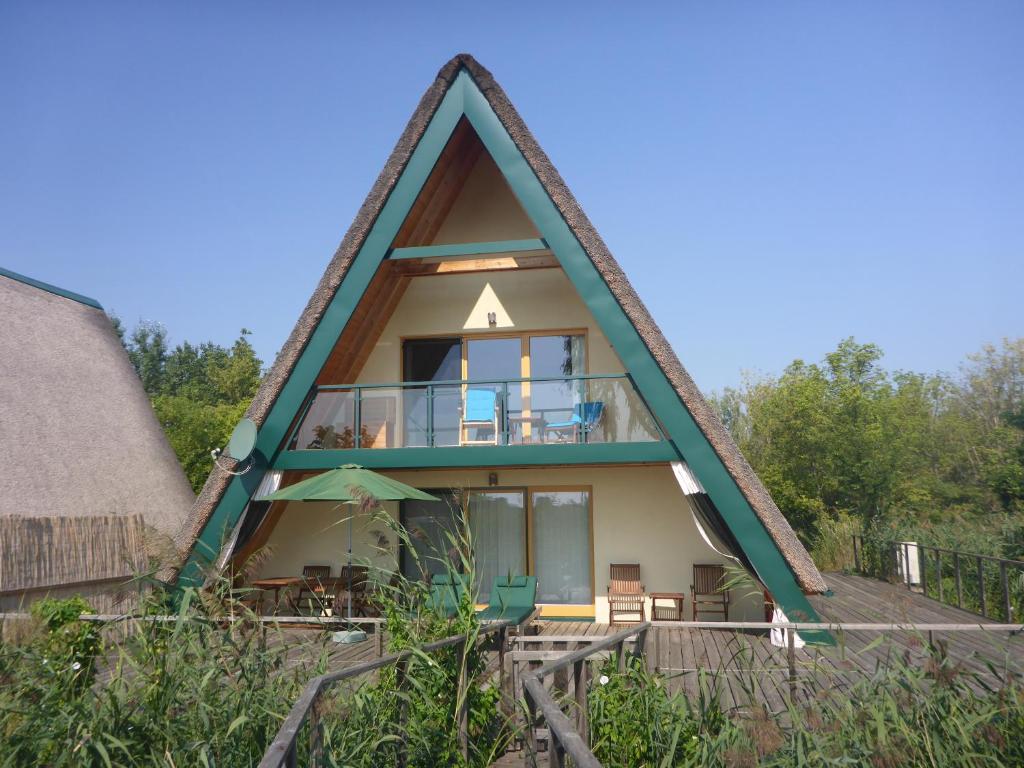 een huis met een rieten dak en een balkon bij Ferienhäuser Finiki in Purbach am Neusiedlersee