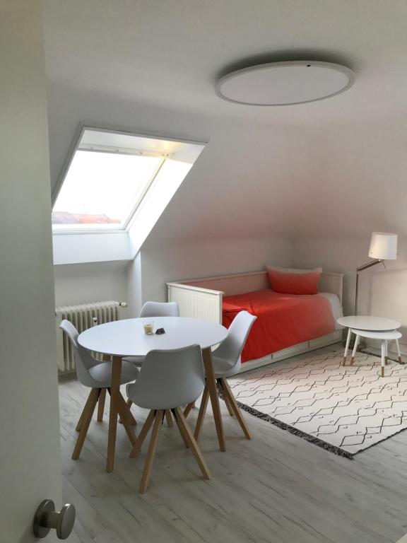 1 dormitorio con cama roja, mesa y sillas en City Apartment gegenüber vom Kurhaus en Freudenstadt