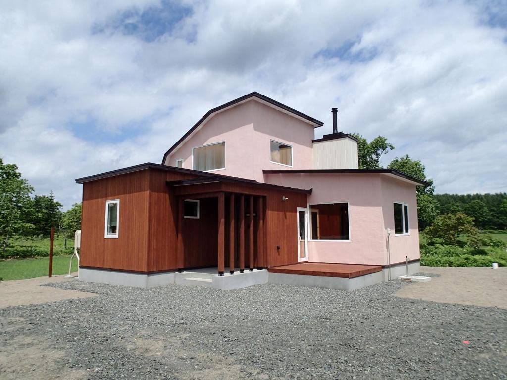uma pequena casa rosa sentada em cima de um lote em Tsukushi Village em Tsurui