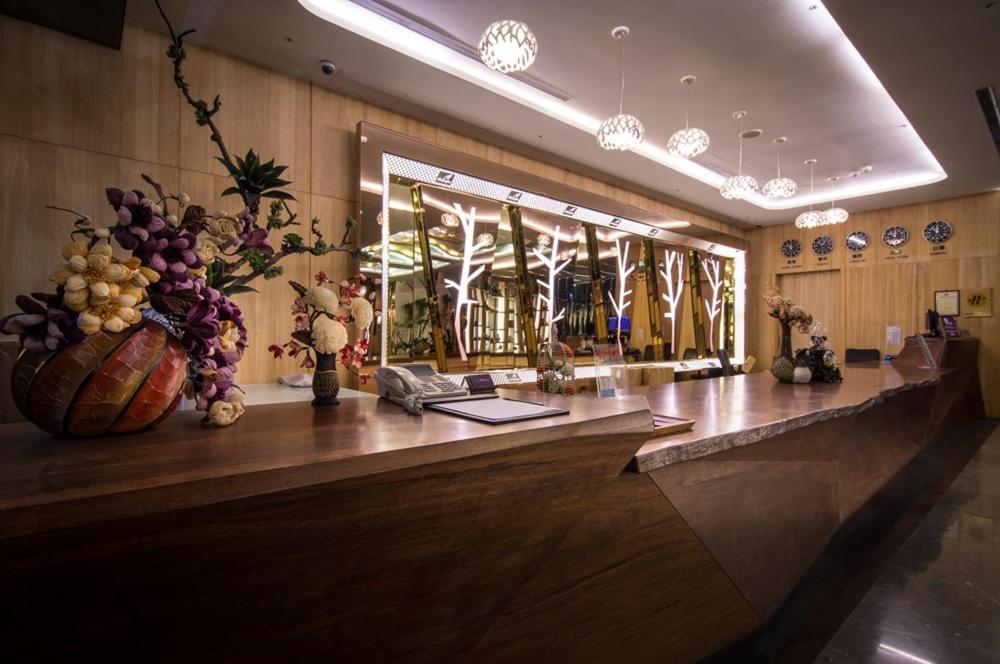 a lobby with a long counter with flowers on it at Shianghu Boutique Hotel in Chiayi City