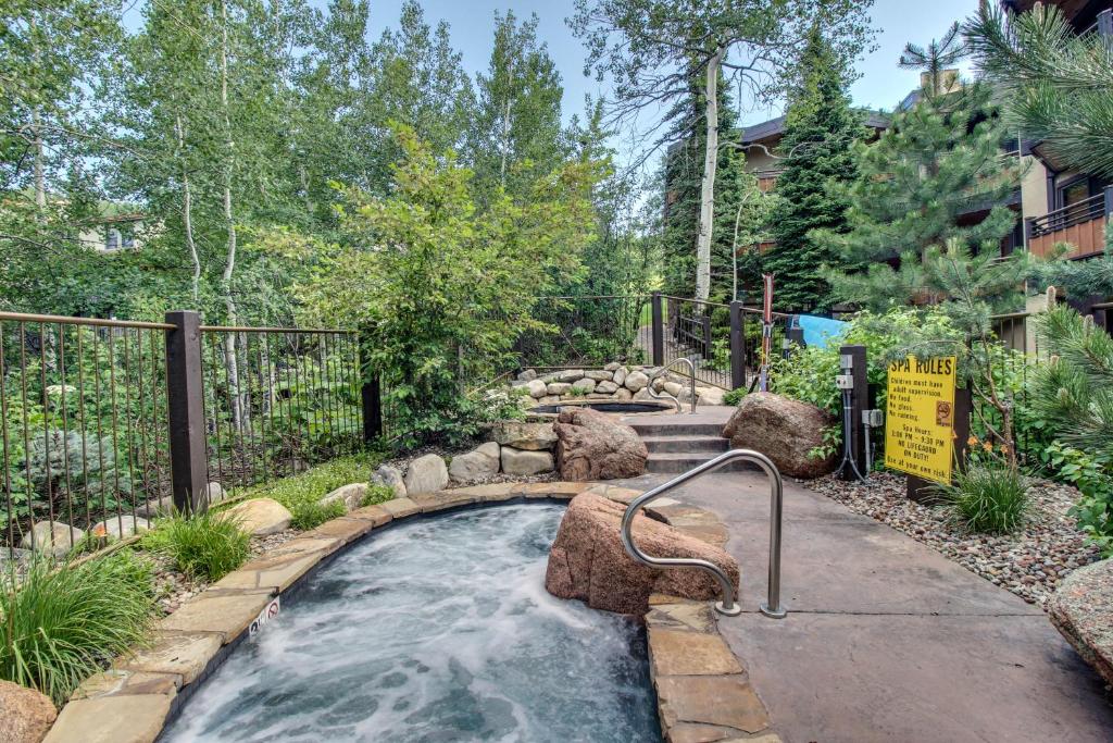 a hot tub in a backyard with rocks and trees at Cozy Slopeside Condo in Snowmass Village