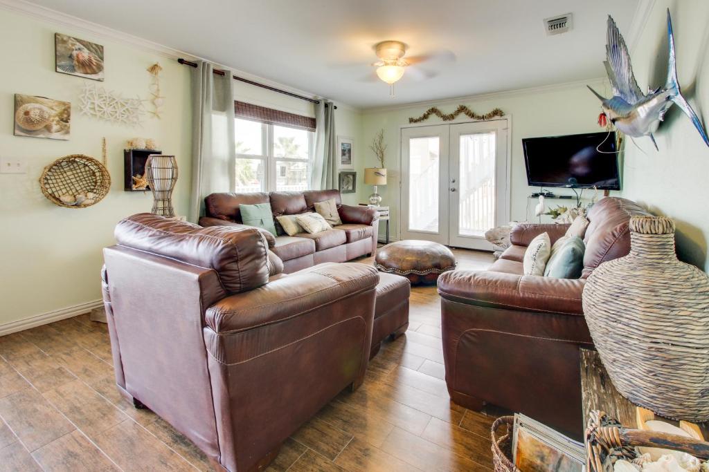 uma sala de estar com dois sofás de couro e uma televisão em Mesquite House Upstairs Unit em South Padre Island