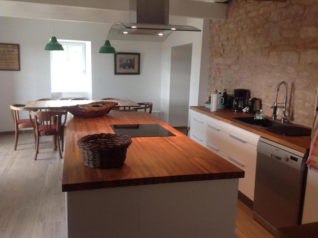 - une cuisine avec un comptoir en bois et une table dans l'établissement Au Pied des Vignes, à Santenay