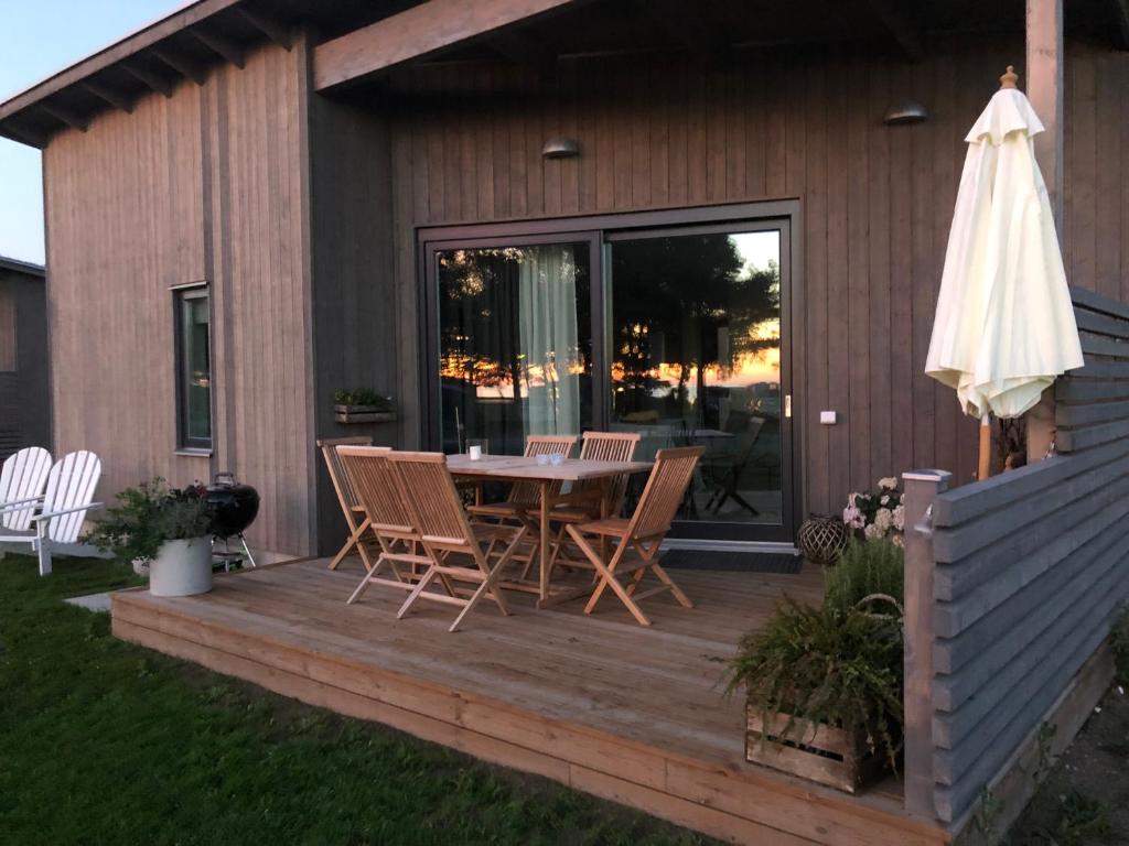 una terrazza in legno con tavolo, sedie e ombrellone di Superfint boende med havsutsikt, Tofta Strand a Visby