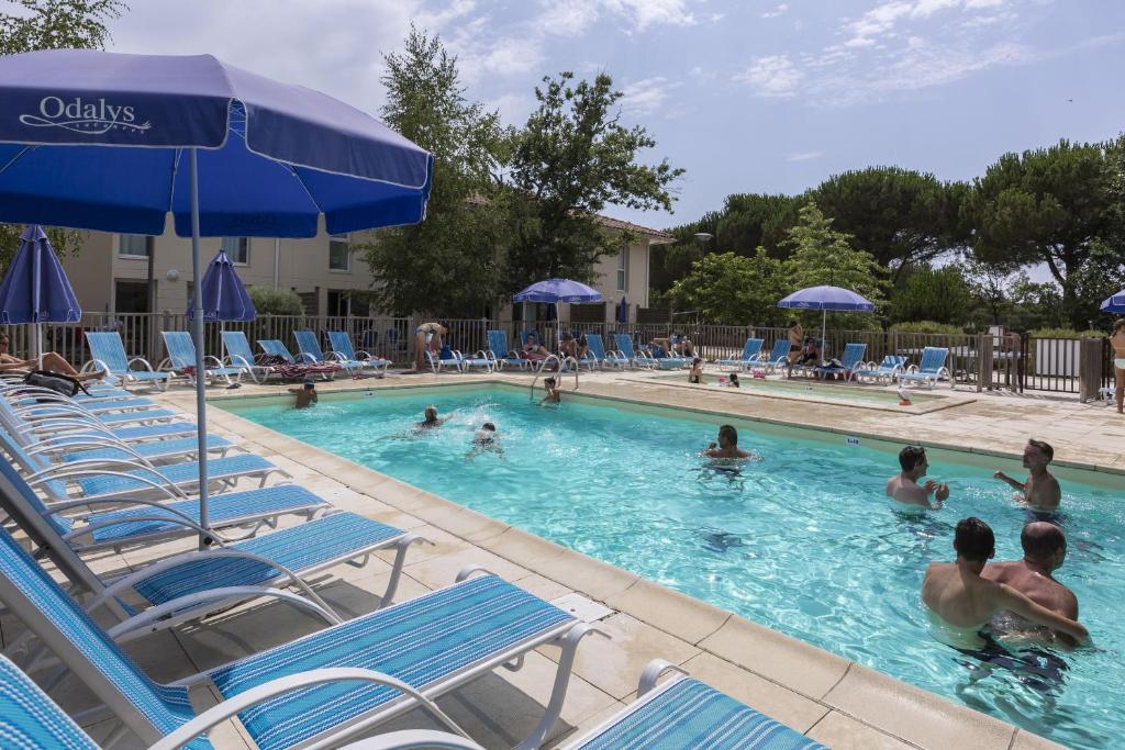 a pool with chairs and people in the water at Résidence Odalys Le Petit Pont in Hourtin