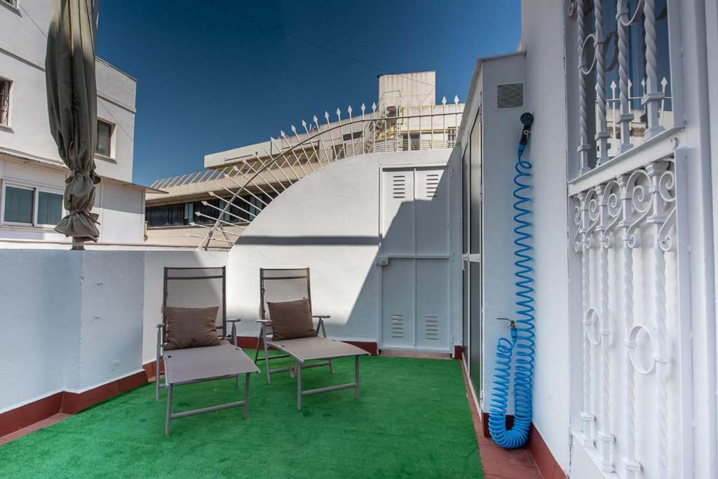un balcón con 2 sillas y una tabla de surf. en Ático Campana Donkey Terraza privada, en Sevilla