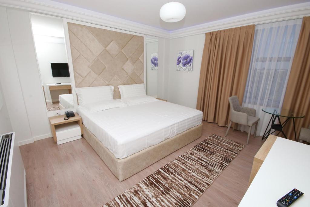 a bedroom with a large white bed and a desk at ELJOS HOTEL in Fushë-Krujë