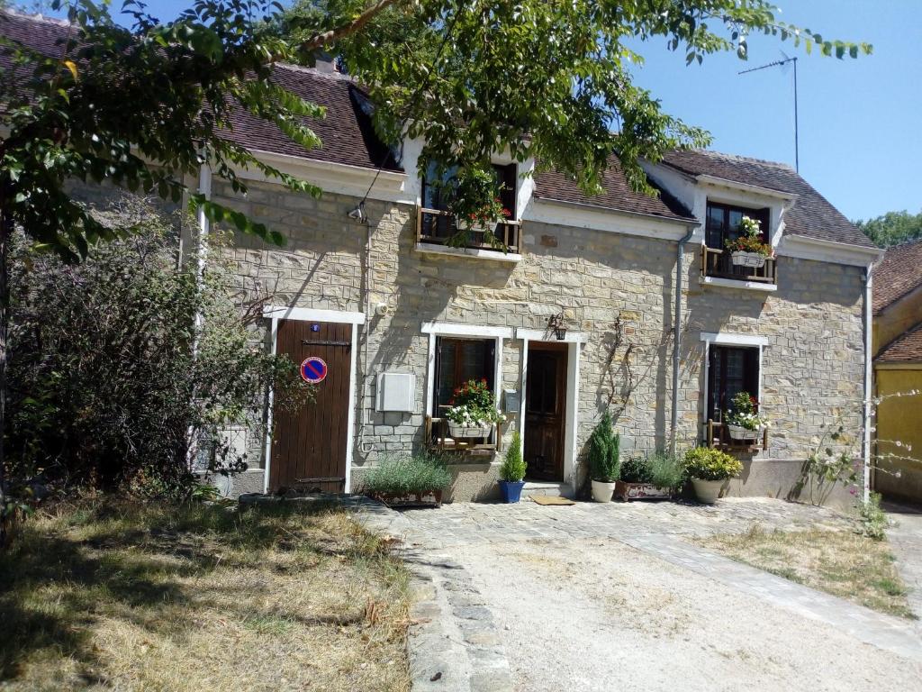 a stone house with potted plants on the windows at Charmante Maison à Recloses in Recloses