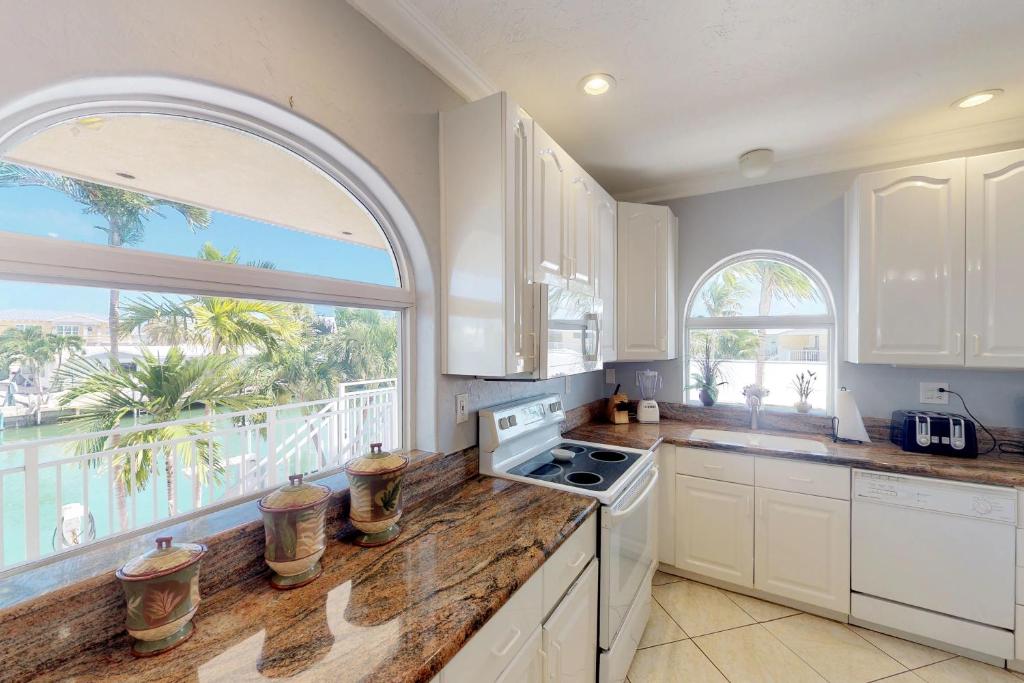 a kitchen with white cabinets and a large window at Dream in the Keys in Key Colony Beach