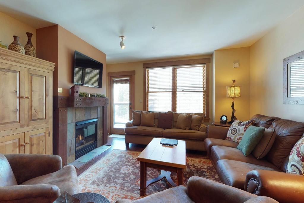 a living room with leather furniture and a fireplace at Springs Lodge 8888 in Keystone