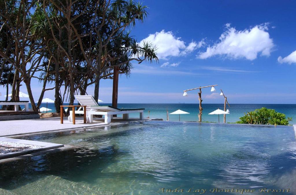 a swimming pool with a bench and the ocean at Andalay Boutique Resort in Ko Lanta