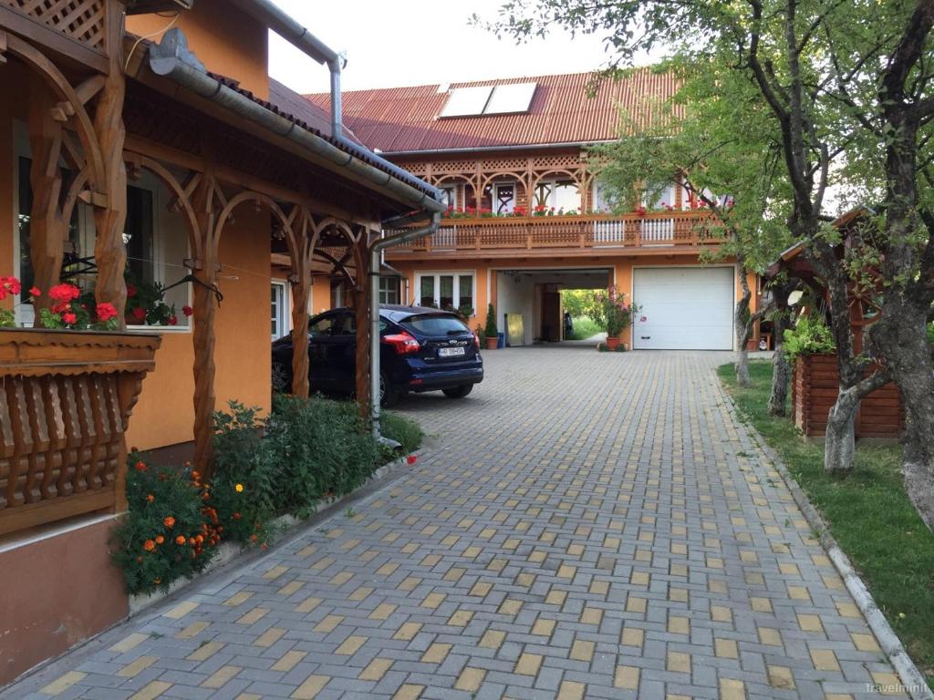 a car parked in front of a building with a driveway at Pensiunea Fenyő in Corund