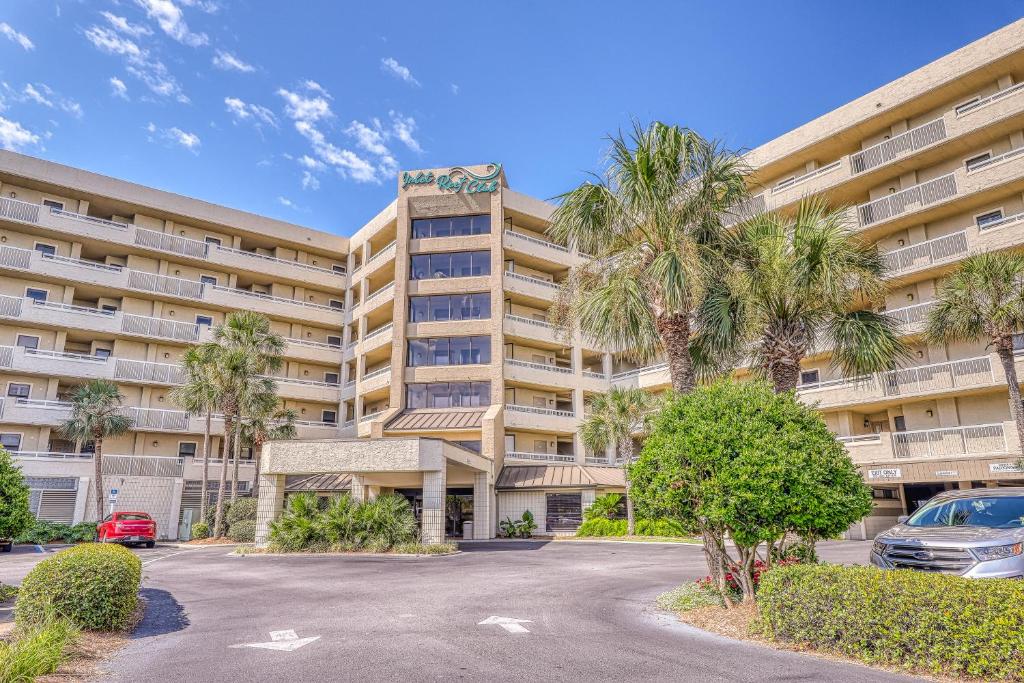 a large apartment building with palm trees in a parking lot at Inlet Reef in Destin