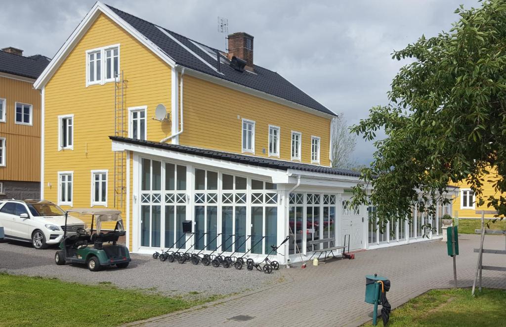 une grande maison jaune et blanche avec une voiture garée devant dans l'établissement Melleruds Golfklubb Bed & Breakfast, à Mellerud