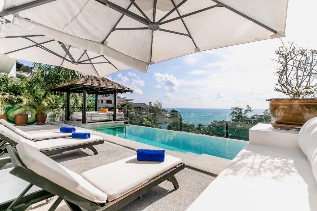 a villa with a swimming pool and an umbrella at Surin Heights Villa in Surin Beach