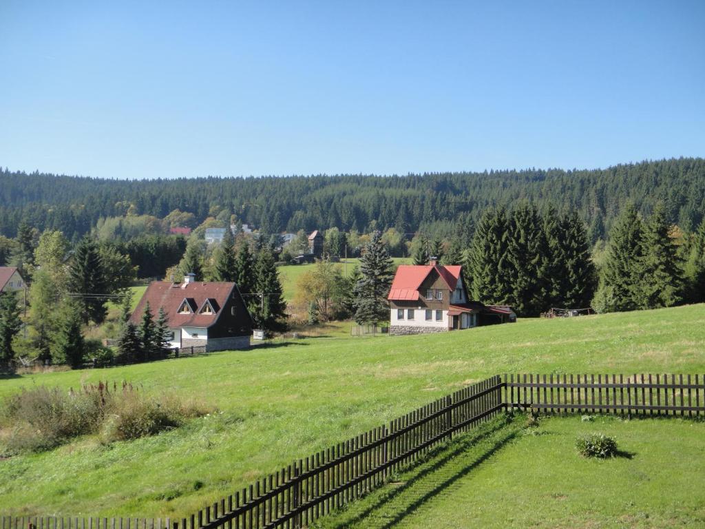 a field with a fence and houses in the background at Pension MAX in Pernink
