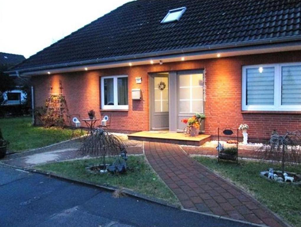 ein rotes Backsteinhaus mit einer Eingangstür und einer Veranda in der Unterkunft Orchidee in Niebüll