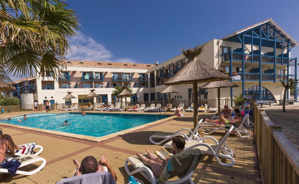 - un groupe de personnes assis sur des chaises au bord de la piscine dans l'établissement Résidence Odalys Du Port, à Hourtin