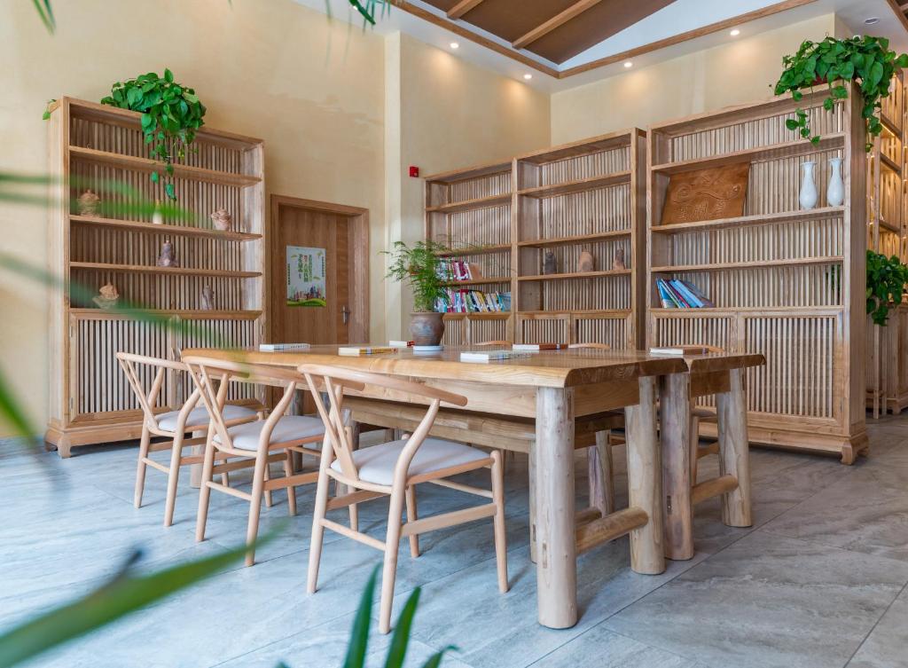 a large wooden table and chairs in a room with book shelves at Yunxianju Tea Culture Theme Hotel in Kunming
