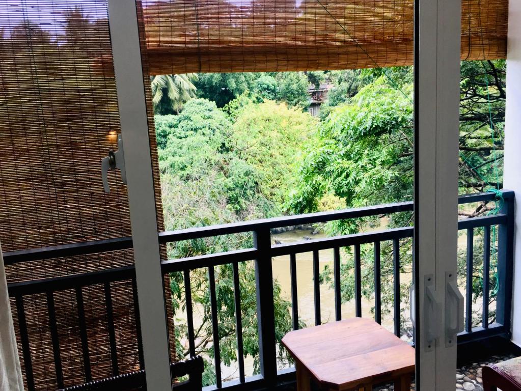 een balkon met een tafel en uitzicht op het bos bij Jenushi homestay in Kandy