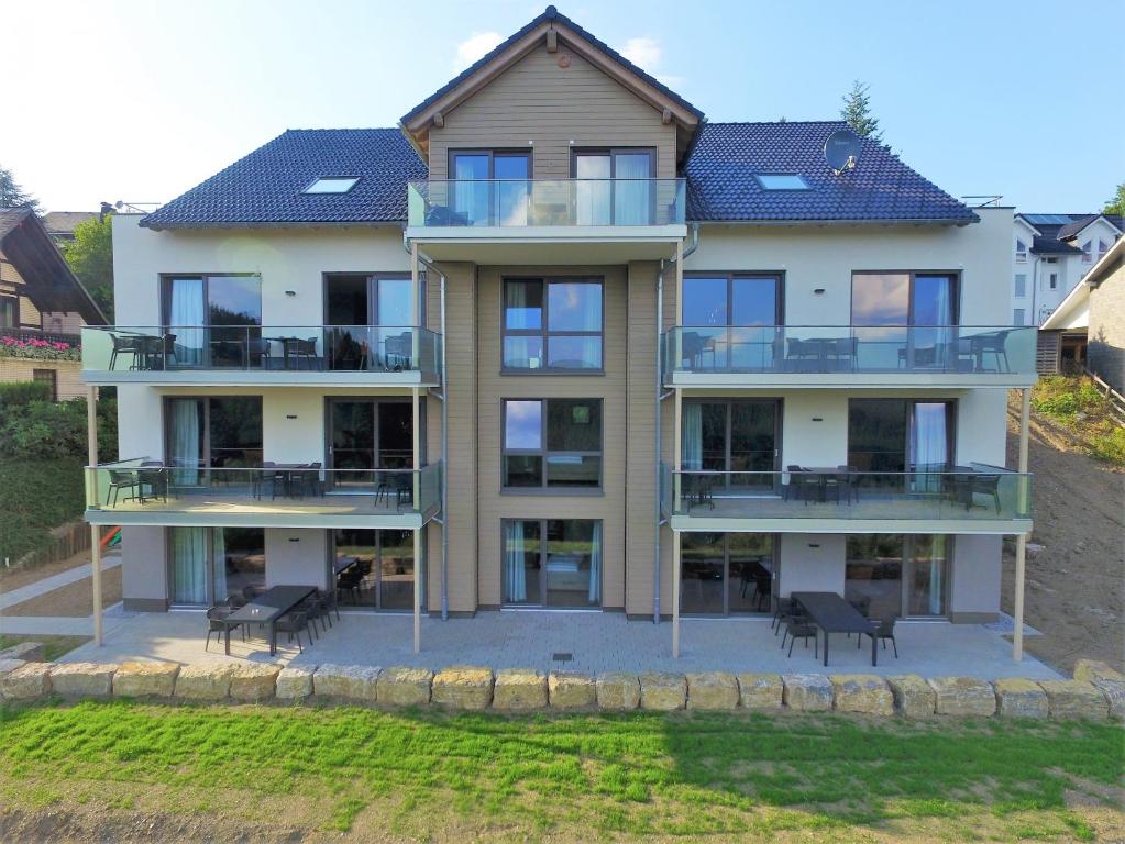 an apartment building with balconies and tables and chairs at UplandParcs Bergblick in Winterberg