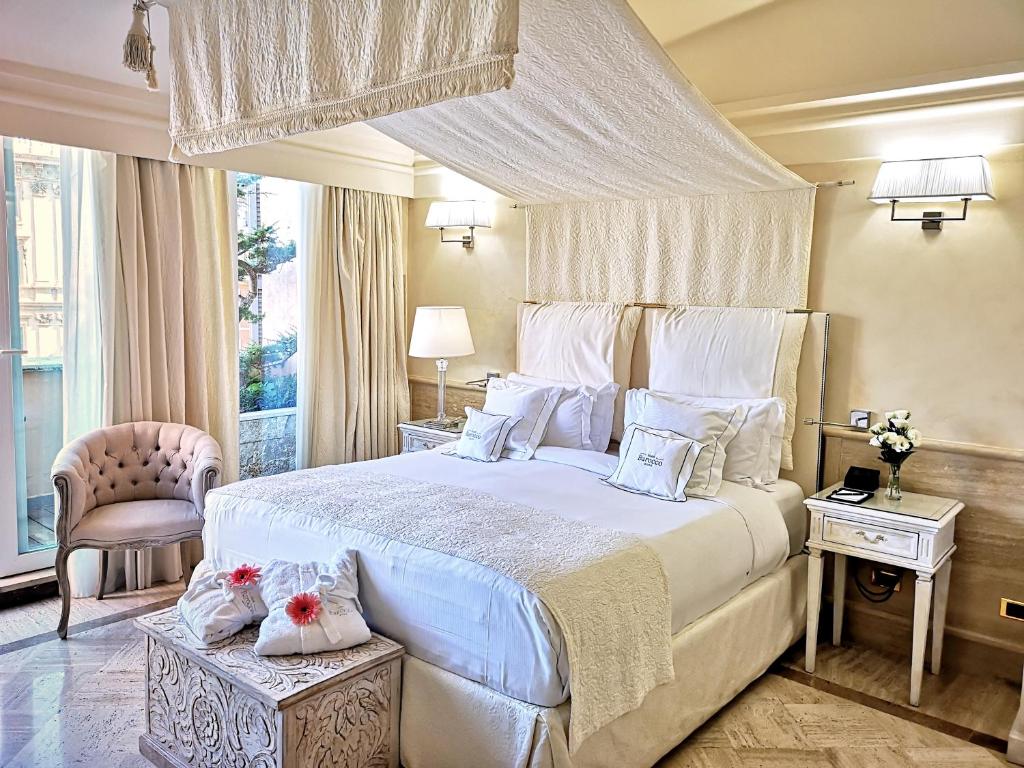 a bedroom with a large white bed with white pillows at Hotel Barocco in Rome