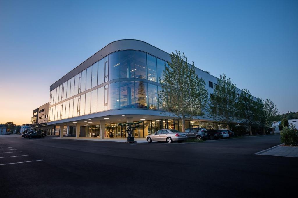 a large glass building with a car parked in front at Hotel Meilenstein in Langenthal