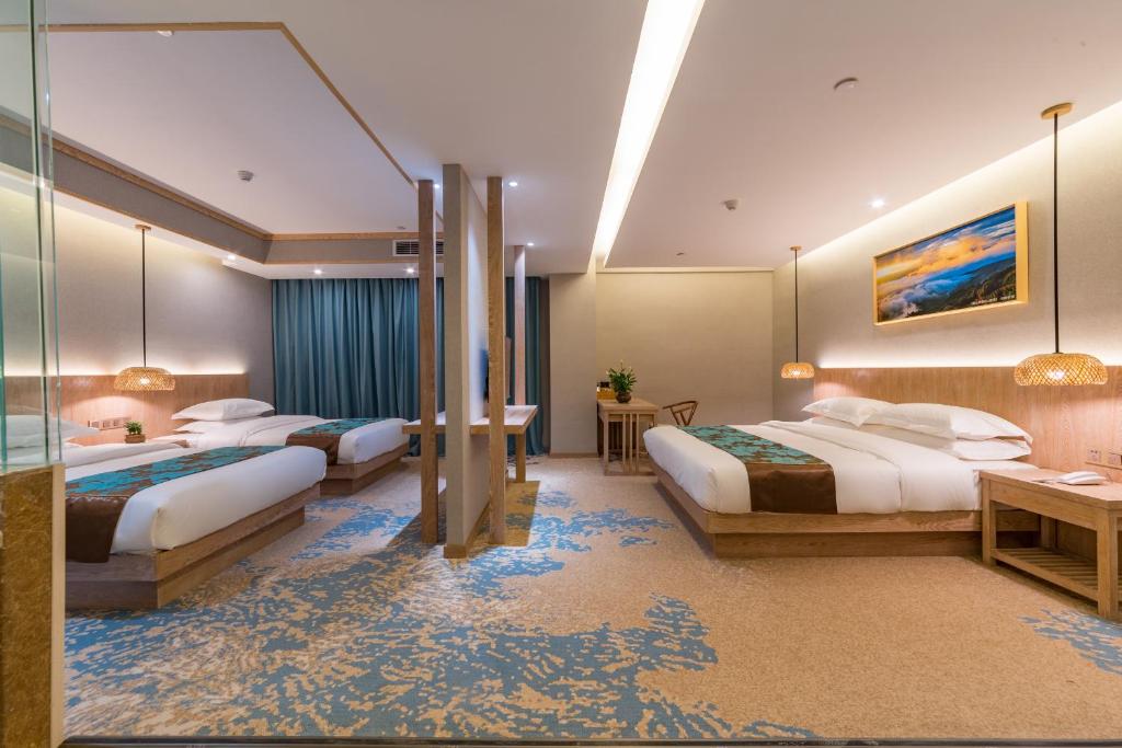 a hotel room with three beds in a room at Yunxianju Tea Culture Theme Hotel in Kunming