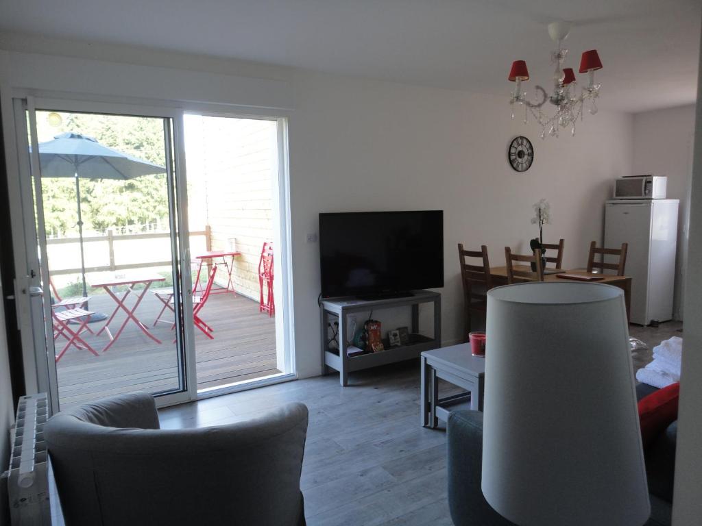 sala de estar con TV, mesa y sillas en Le Hameau du Peu, en Châteauvieux