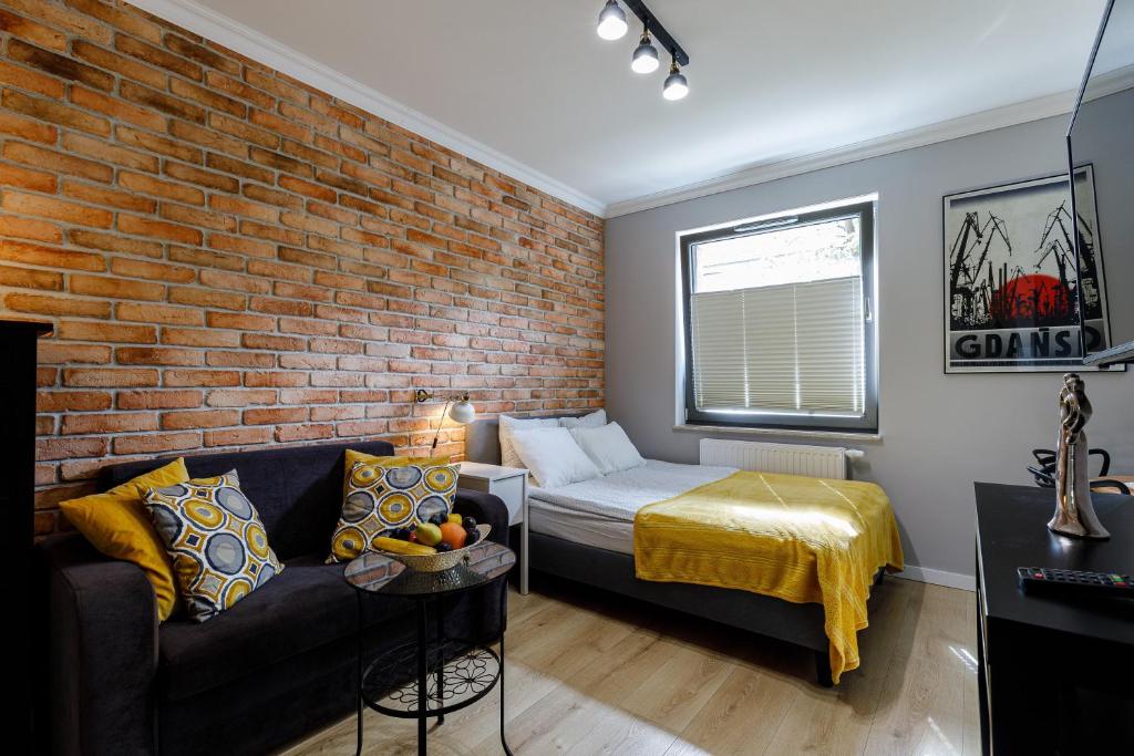 a living room with a couch and a brick wall at Apartamenty Przytulne z parkingiem rowerowym, dostępem sauny- bicycle parking and access to the Sauna in Gdańsk