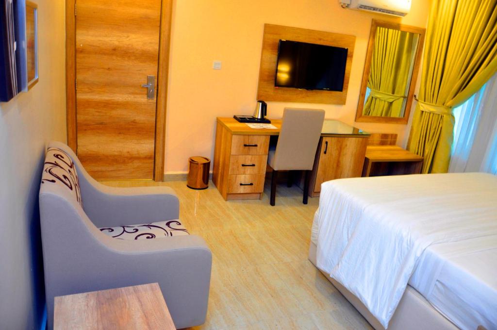 a hotel room with a bed and a desk and a table at Lit Suites in Abuja