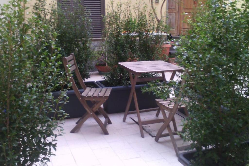 a wooden table and two chairs next to some plants at la casetta nel cortile in Catania