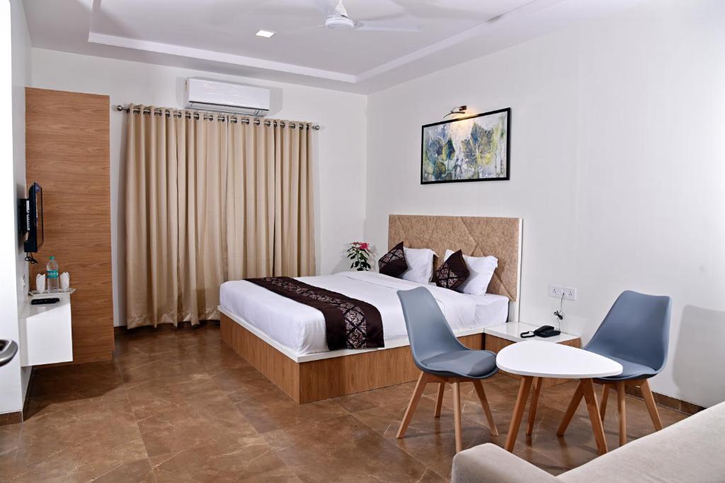 a hotel room with a bed and a table and chairs at Hotel Grand Ecotel, Aurangabad in Aurangabad