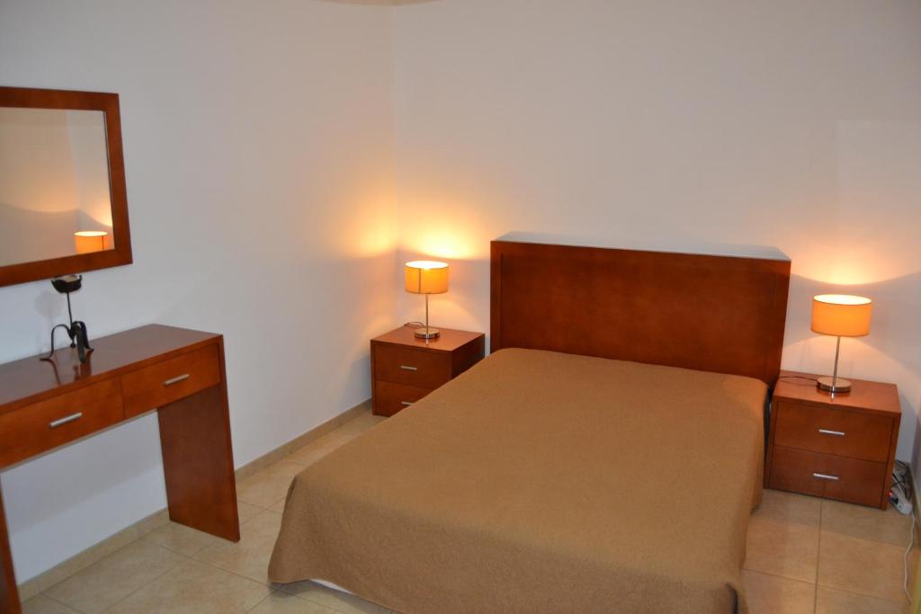 a bedroom with a bed and two night stands with lamps at Apartamento - 2 a 4 Pessoas- Piscina in Olhos de Água