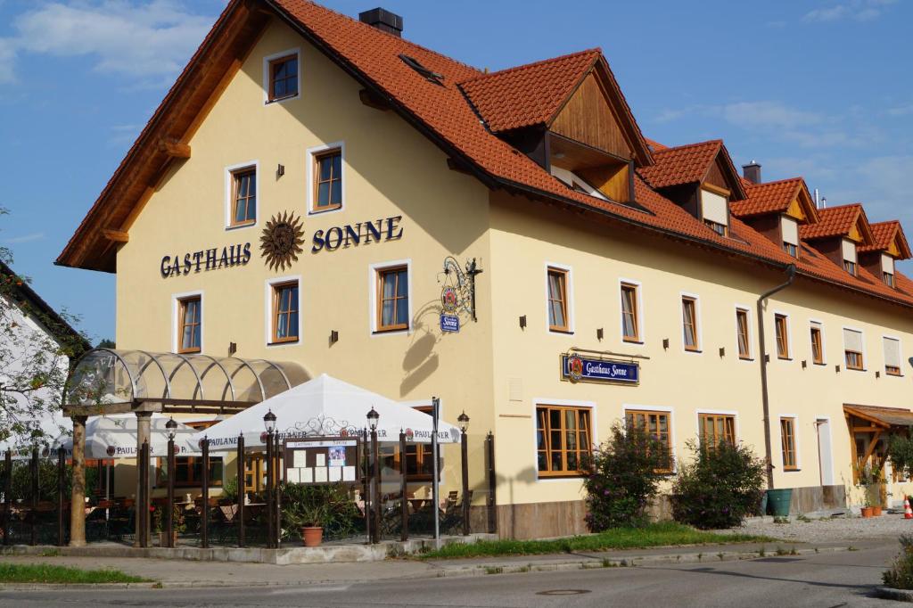 un gran edificio blanco con techo rojo en Hotel Gasthaus Sonne en Peißenberg