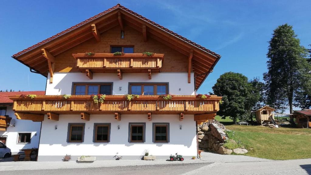 a house with a wooden balcony on top of it at Ferienhof Schmalzgrub in Böbrach