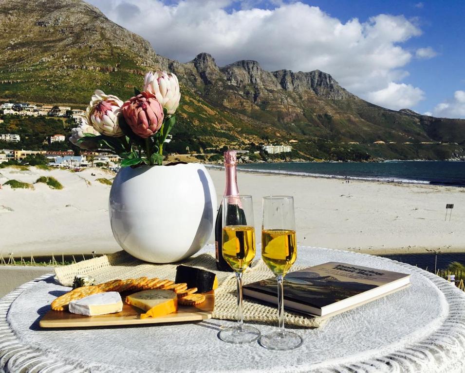 a table with a vase of flowers and wine glasses at Beach Club 8 in Hout Bay