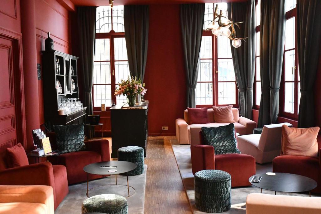 a living room with red walls and chairs and tables at Hotel 'T Sandt in Antwerp