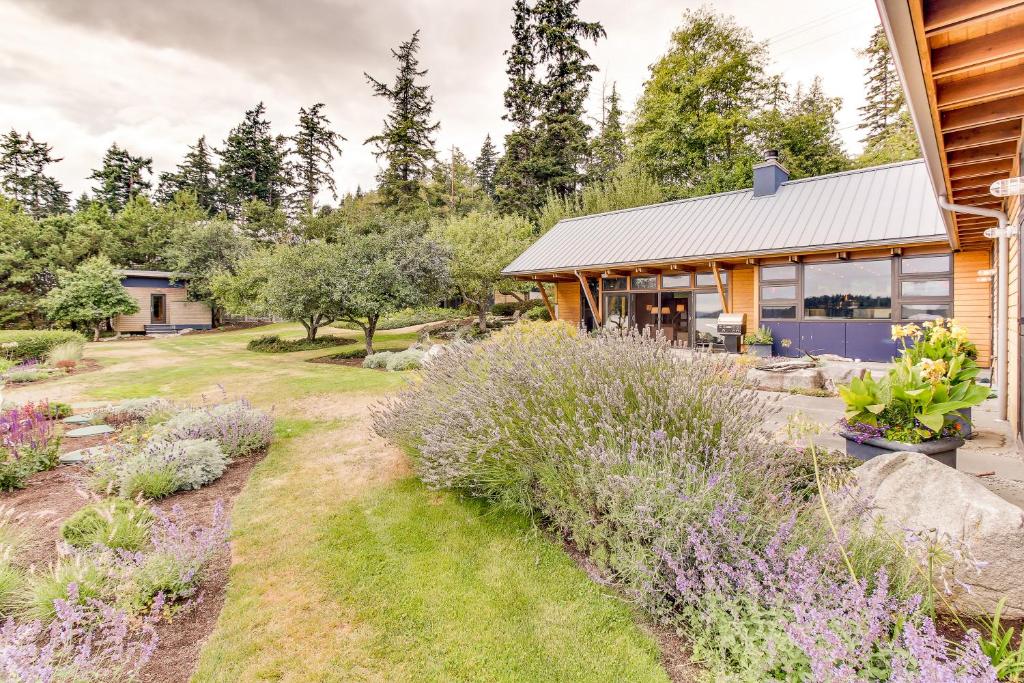 a garden in front of a house with purple flowers at Fidalgo Island Waterfront Stunner in Anacortes